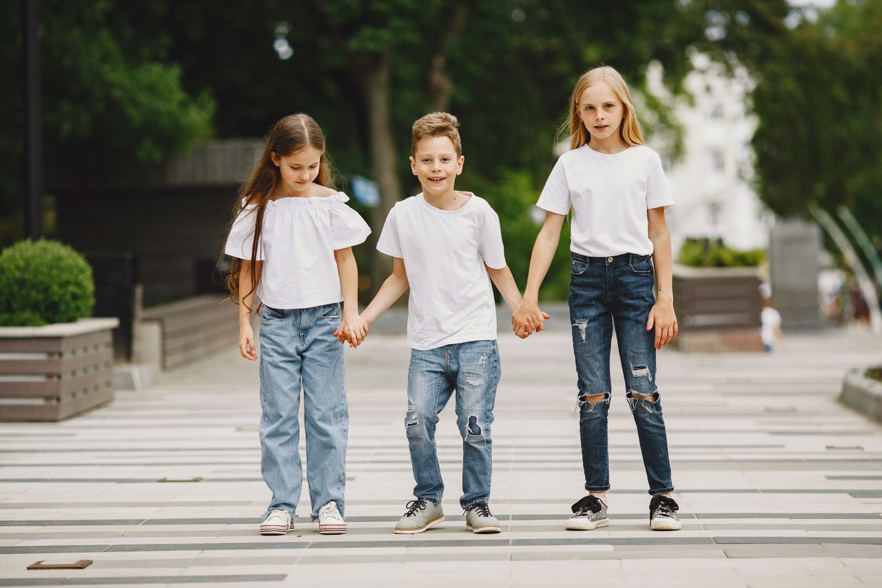 Mastering the First Impression: Your intriguing post title goes here Three children in white t-shirts and jeans holding hands outdoors on a summer day.